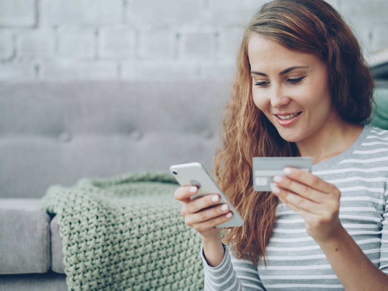 Woman completing a mobile checkout with phone and credit card